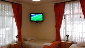 a bedroom with two beds and a tv on the wall at Heritage Inn in Quito