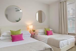 two beds with pink and green pillows in a room at Walk to Toyota Stadium in Frisco