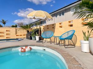a swimming pool with two chairs and an umbrella at Mount Eden Motel in Auckland