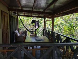 a porch of a house with a chair and a table at Canopy cottage in Honiara