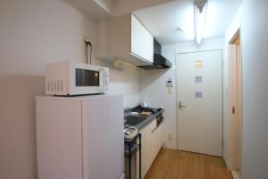 a kitchen with a microwave on top of a refrigerator at オンブラージュ九品寺203-無料駐車場付き-繁華街まで徒歩圏内-南向きで明るいワンルーム in Kumamoto