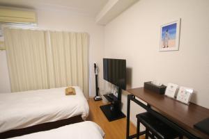 a bedroom with a bed and a desk with a television at オンブラージュ九品寺203-無料駐車場付き-繁華街まで徒歩圏内-南向きで明るいワンルーム in Kumamoto
