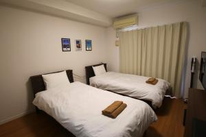 two beds in a room with two towels on them at オンブラージュ九品寺203-無料駐車場付き-繁華街まで徒歩圏内-南向きで明るいワンルーム in Kumamoto