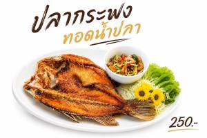 a plate of food with a fish and a bowl of salad at on and on haus in Ban Na Nian