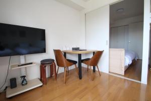 a living room with a table and chairs and a tv at オンブラージュ704号室-無料駐車場付き-繁華街まで徒歩圏内-南向きで明るいワンルーム in Kumamoto