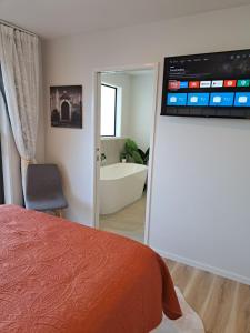 a bedroom with a bed and a bathroom with a tub at Kupe Boutique House with ensuite free wifi in Whitianga