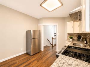a kitchen with a stainless steel refrigerator and wooden floors at Journal Sq PATH - Private Queen Room - Private Bath - Shared Kitchen - 15 Min to NYC in Jersey City