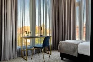 a hotel room with a desk and a bed and a window at Liberté 33, an Ascend Collection Hotel in Poznań