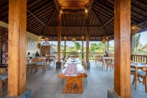 a restaurant with wooden columns and tables and chairs at Dewi Kunti Villa in Tegalalang
