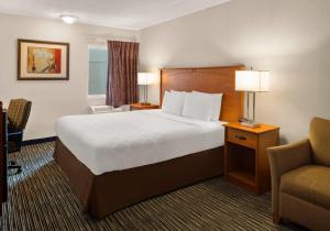 a hotel room with a large bed and a chair at Park Inn by Radisson, Detroit Metro Airport in Romulus +58 photos