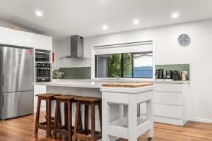 a kitchen with a white counter and stools at Stockton Coastal Escape in Stockton +11 photos