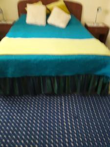 a bed with blue and yellow sheets and pillows at Departamento Duplex Centro Pucon in Pucón