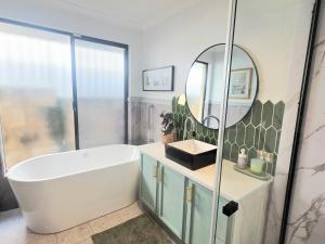 a bathroom with a large tub and a mirror at Homestay in Coogee