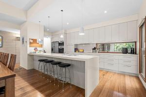 a kitchen with white cabinets and bar stools at 9 Doors From Front Beach in Point Lonsdale