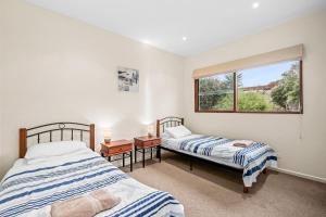 two beds in a room with a window at 9 Doors From Front Beach in Point Lonsdale