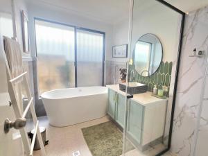 a bathroom with a bath tub and a mirror at Homestay in Coogee
