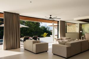 a living room with chairs and a ceiling fan at Mandalore Villas Ubud - Adults Only in Ubud
