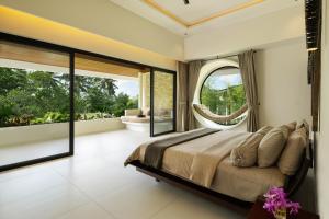 a bedroom with a large bed and large windows at Mandalore Villas Ubud - Adults Only in Ubud