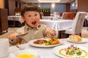 a young boy sitting at a table eating food at Hotel Epinard Nasu in Nasu