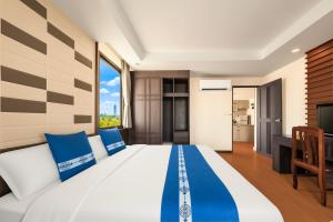 a bedroom with a large bed with blue pillows at Tycoon Holiday Hotel in Pattaya