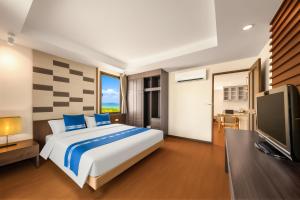 a bedroom with a large bed and a flat screen tv at Tycoon Holiday Hotel in Pattaya