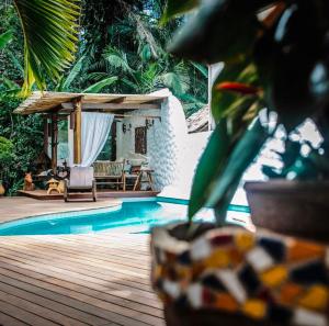 a pool with a wooden deck and a house with a chair at Pousada Luz Do Sol in Porto Seguro