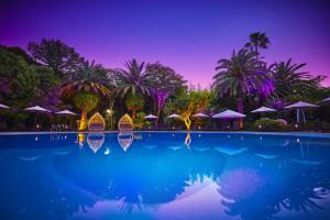 a swimming pool with palm trees and umbrellas at night at Hotel New Otani Makuhari in Chiba