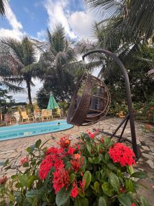 a swing next to a swimming pool with flowers at Recanto das Orquideas in Quatis