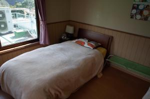 a small bedroom with a large bed with a window at Kashi Besso Takachiho in Takachiho
