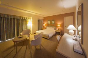 神戸市にある神戸 西神オリエンタルホテルのベッド、テーブル、椅子が備わるホテルルームです。