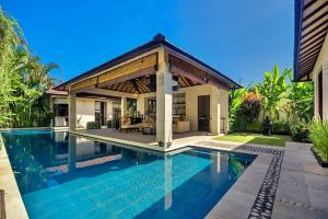 a swimming pool in front of a villa at Arama Riverside in Legian