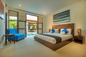 a bedroom with a large bed and a blue chair at Arama Riverside in Legian +19 photos