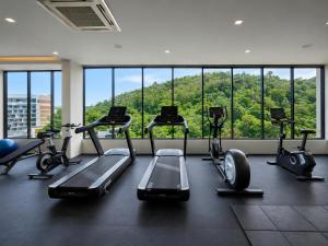 a gym with cardio machines and a large window at Karon Utopia in Karon Beach