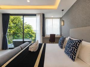 a bedroom with a bed and a large window with a tub at Karon Utopia in Karon Beach
