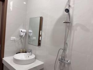 a white bathroom with a sink and a shower at TRƯỜNG THỊNH Hotel in Hòn Tru