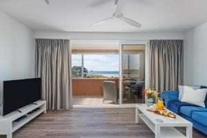 a living room with a blue couch and a tv at Seaview Studio Apartment - Beachfront with Heated Pool in Whitianga