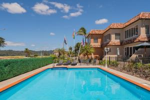 a swimming pool in front of a house at Seaview Studio Apartment - Beachfront with Heated Pool in Whitianga