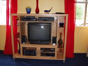 a entertainment center with a television and red curtains at Summit View Lodge in Seward