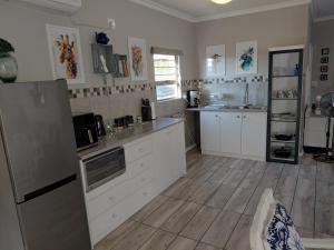 a kitchen with white cabinets and a refrigerator at Naomi's Sky Loft Little Falls in Roodepoort