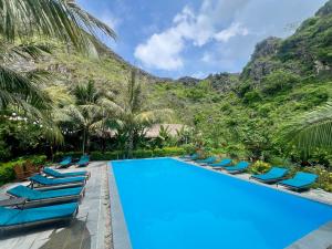 a pool with chairs and mountains in the background at Peaceful Garden Tam Cốc in Ninh Binh