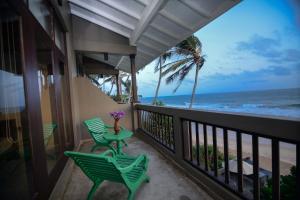 a balcony with chairs and a table and the ocean at At Ease Beach Hotel in Hikkaduwa