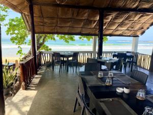 a restaurant with tables and chairs and the beach at Lido Dikwella in Dickwella