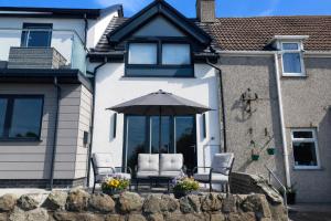 a patio with two chairs and an umbrella in front of a house at 2 Harbour Lights in Cemaes Bay