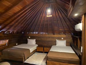 two beds in a room with a roof at Alu Lofts in Seminyak