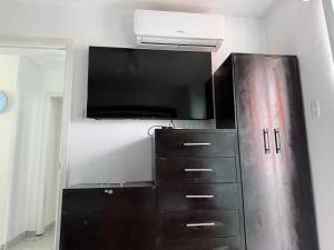 a black refrigerator with a tv and a dresser at Departamento moderno con jacuzzi privado - Porto Vitoria in Tonsupa
