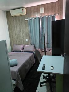 a room with a bed and a desk and a television at Pousada Dubai in Cuiabá