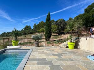 a swimming pool with palm trees and a fence at Les Grandes Conches in Valensole