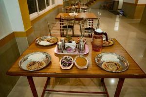 a wooden table with plates of food on it at Iyal Hotels and Resorts in Salem