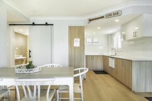 a kitchen with a wooden table and white chairs at Apartment 4B in Lennox Head +9 photos