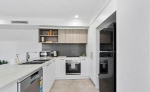 a white kitchen with a sink and a refrigerator at Gemstone in Morayfield